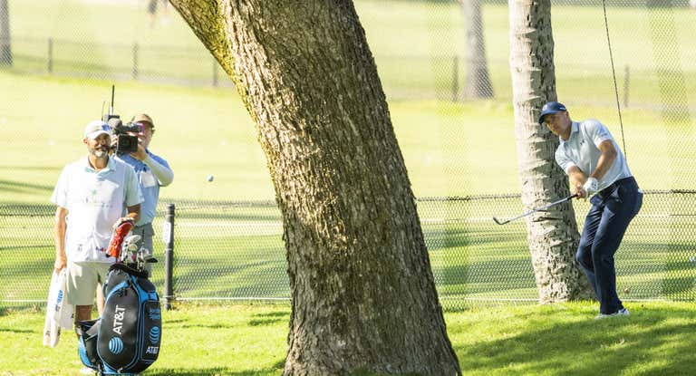 Jordan Spieth golpea desde detrás de un árbol tras no coger calle.
