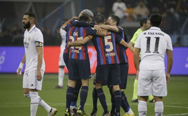 Los jugadores del Barça se abrazan ante Benzema y Asensio, cabizbajos.  EFE