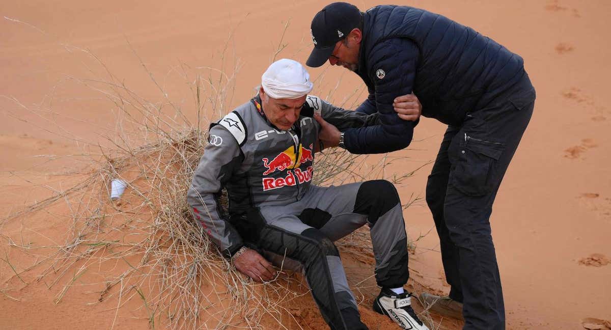 Carlos Sainz, atendido por un médico, tras su accidente en el Rally Dakar. /AFP