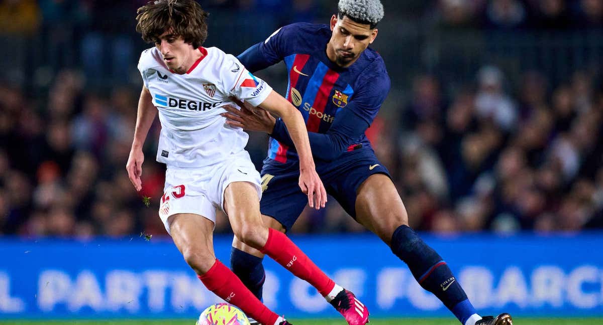 Bryan Gil intenta zafarse de Araújo durante la disputa del último Barça - Sevilla. /Getty