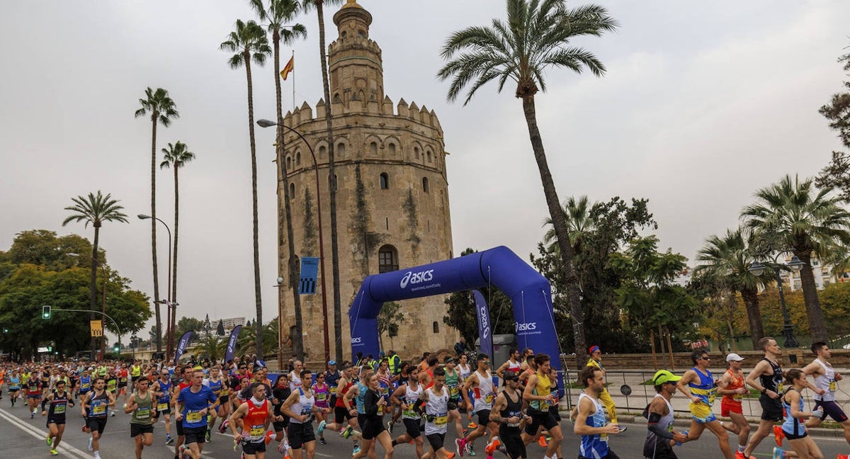 Participantes en el Maratón de Sevilla pasan por la Torre del Oro.