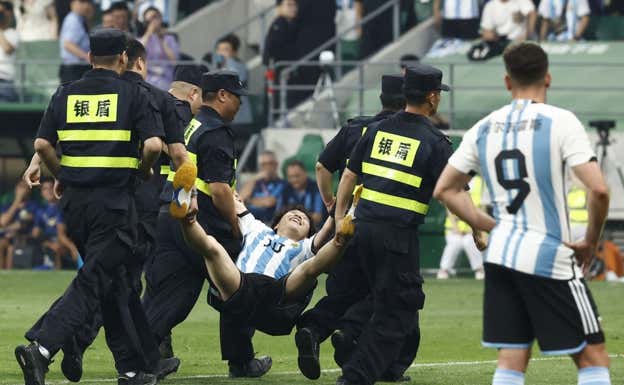El espontáneo es retirado del terreno de juego tras abrazar a Messi.
