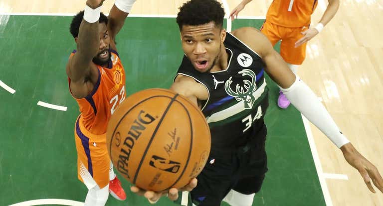 Giannis Antetokounmpo entra a canasta ante DeAndre Ayton.
