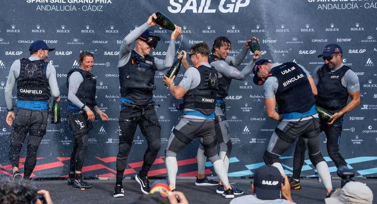 Jimmy Spithill baña con champán a sus compañeros del Team USA.
