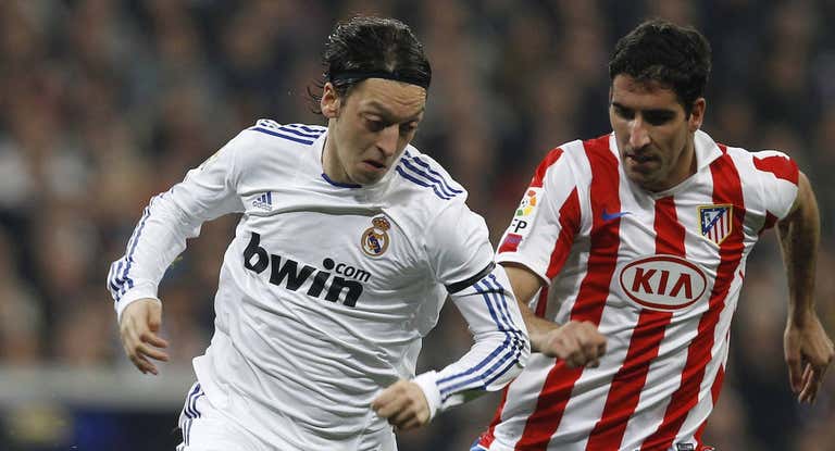 Özil, con Raúl García en un Real Madrid-Atlético.