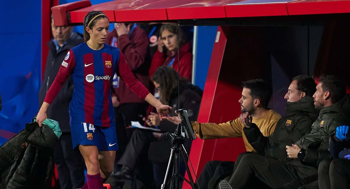 Aitana Bonmatí choca la mano al técnico del FC Barcelona, Jonatan Giráldez, que está en el banquillo con su cuerpo técnico.