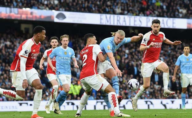 Haaland lanza a portería en el choque ante el Arsenal, rodeado de jugadores gunners.  EFE