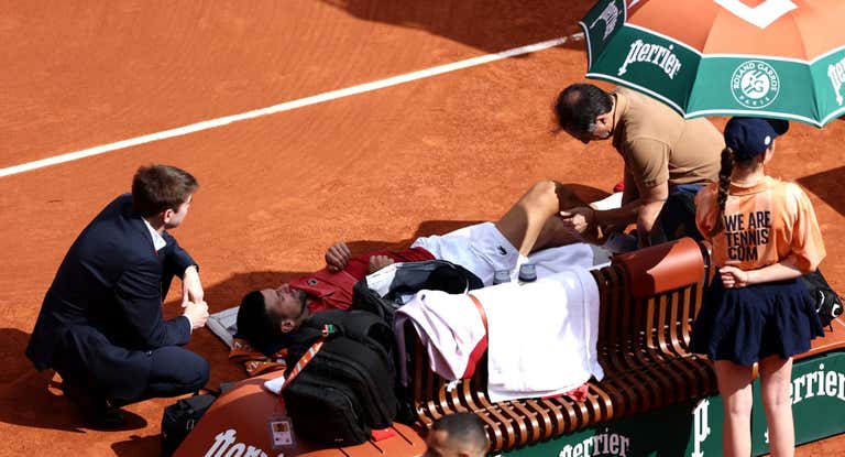 Novak Djokovic, mientras es atendido por los médicos por el problema en la rodilla.