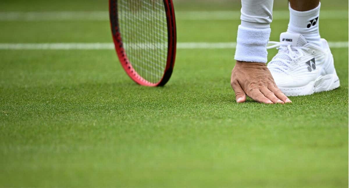 Un tenista comprueba el estado del césped en Wimbledon. /AFP