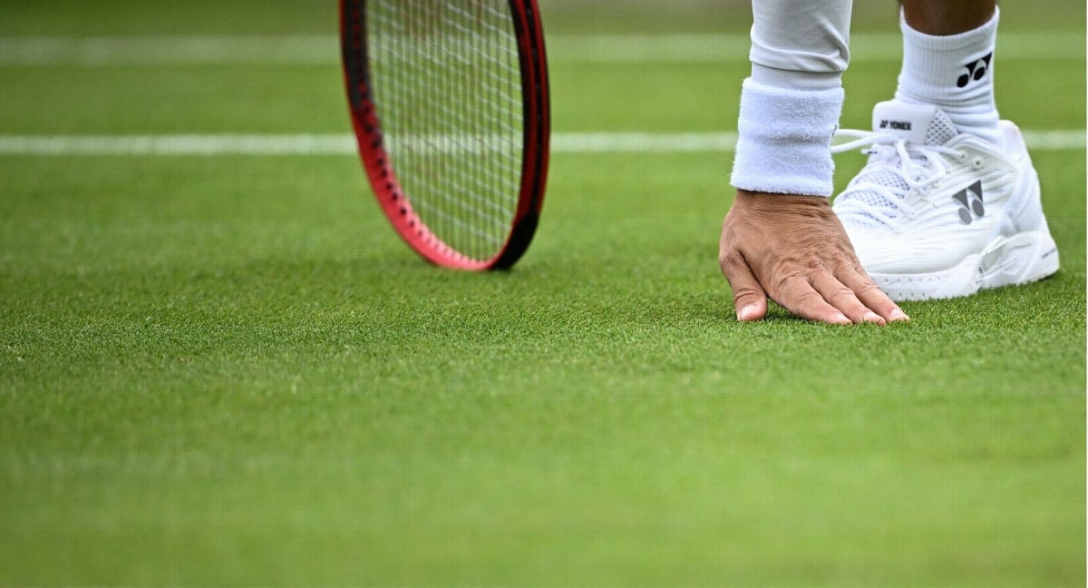 Un tenista comprueba el estado del césped en Wimbledon.