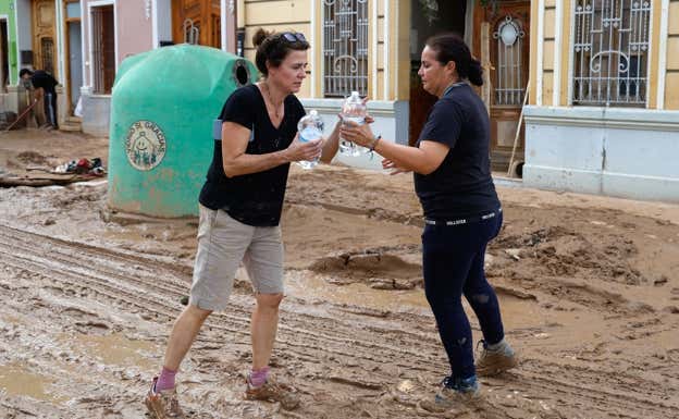 Dos mujeres acercan agua a los afectados en Picanya.  EFE