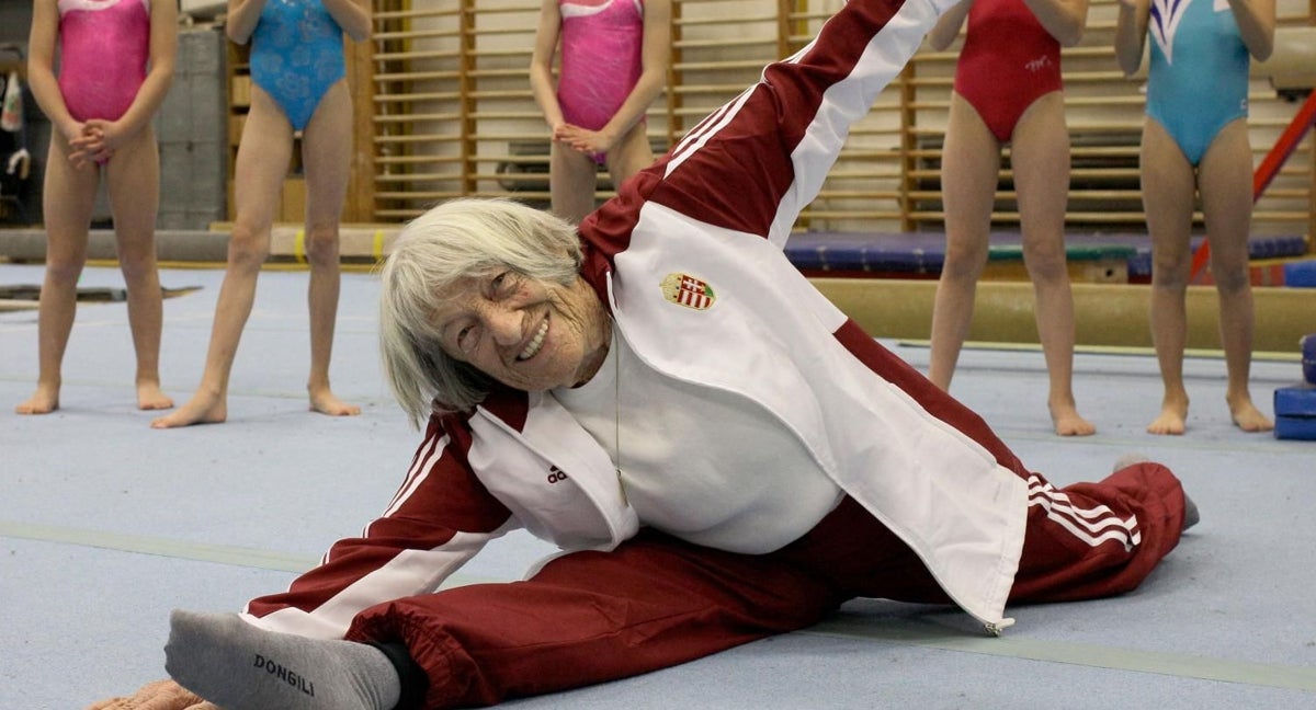 Agnes Keleti, con 95 años, hace un split delante de jóvenes gimnastas húngaras.