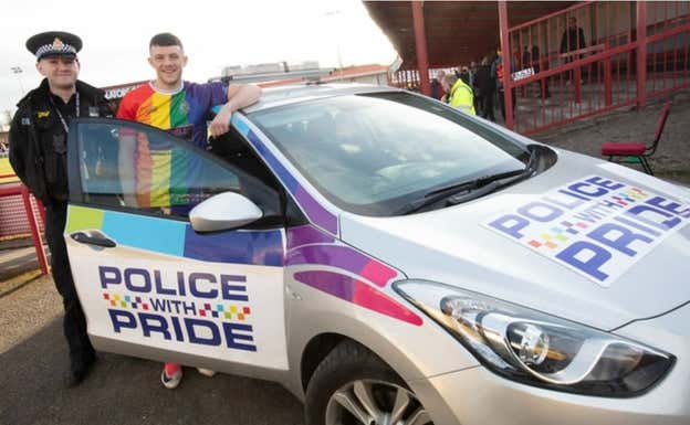 El capitán del Altrincham con un policía y el coche patrulla LGTBI.  Greater Manchester Police