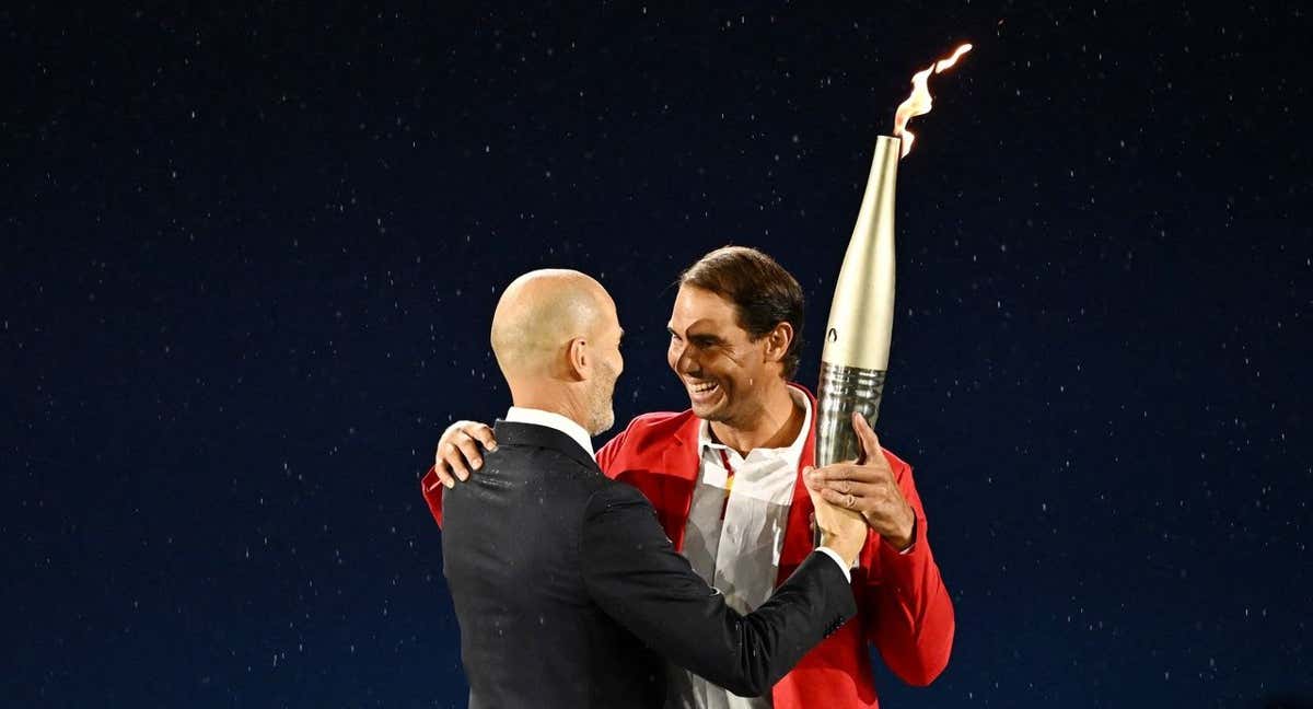 Zinedine Zidane entrega la antorcha olímpica a Rafael Nadal en el momento cumbre de la ceremonia de París 2024. /REUTERS/Dylan Martinez