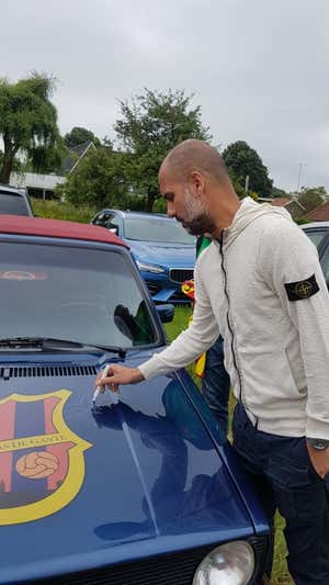 Pep Guardiola firma el coche de Carlos Díaz.  PEÑA BARCELONISTAS DE GANTE
